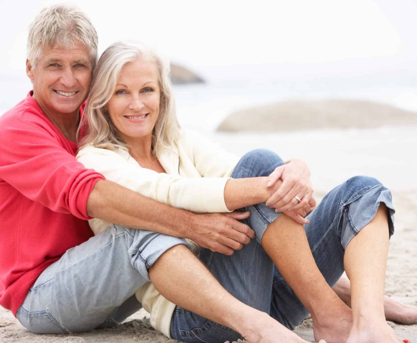 Senior Couple On Holiday Sitting On Winter Beach