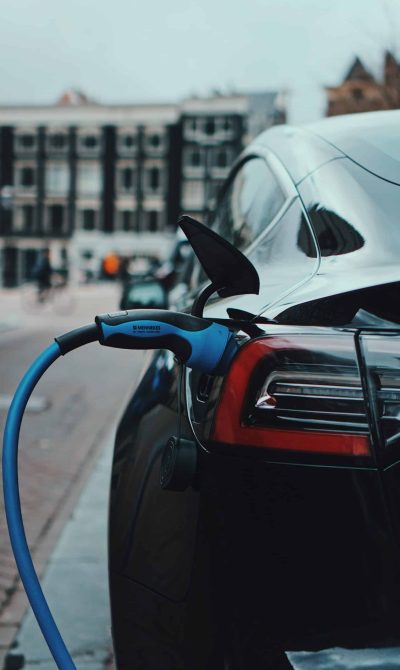 Voiture électrique noir à une borne de recharge avec le pistolet à recharge de couleur bleu